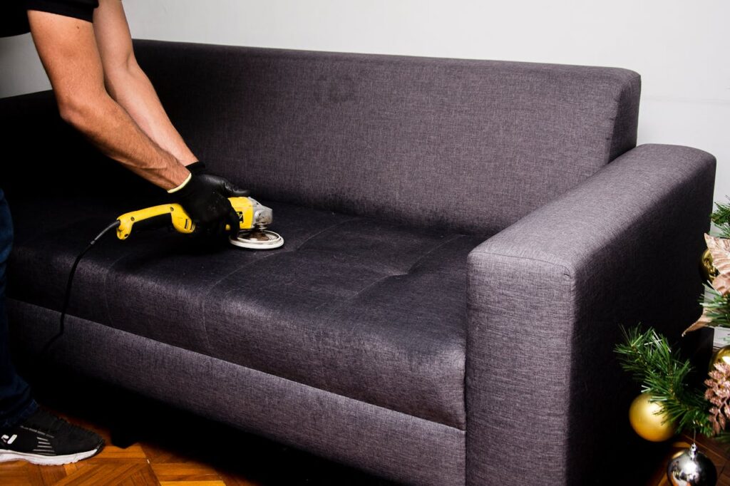 A professional performs sofa cleaning with a grinder in an indoor setting, showcasing efficient service.